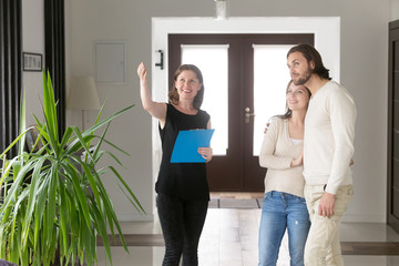 Three person standing in hallway. Smiling real estate agent, realtor showing property house for sale or tenant to young happy married couple. New home, moving and realestate loan and mortgage concept