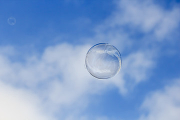 A soap bubble is floating in the air isolated on blue sky