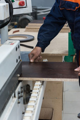 Furniture production or craft concept: worker making the wood surface of furniture part with special machine