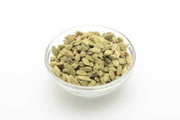 Cardamomo en un bol de cristal transparente sobre fondo blanco