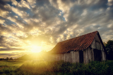 Obraz premium On an acre stands an old woodshed. Here during a sunset: Concept: Landscapes or Sunset