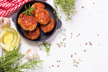 Homemade cutlets and herb and spices  on  frying pan on light textured background.