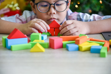 Asian boy are practicing skills By assembling wooden parts, Geometry, according to their own...