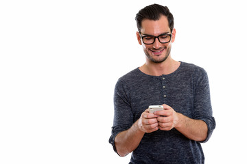 Studio shot of happy young handsome man smiling and using mobile