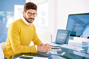 Fototapeta na wymiar Handsome young man using laptop while working in the office