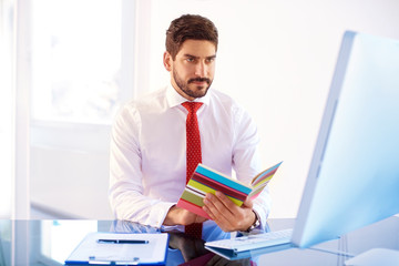 Businessman sitting in the office and holding hands a diary