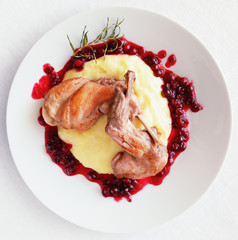 fried rabbit legs stewed with white wine, rosemary, and cranberries on potato mash with cranberry sauce decorated with fried rosemary