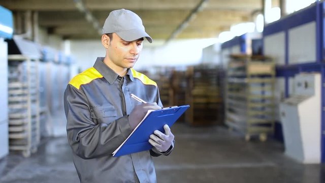 Pensive industrial worker writing on a document