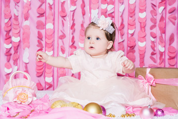 Obraz na płótnie Canvas Baby girl with a Christmas balls in a festive pink interior