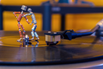  two funny small human figures, roughly welded together from resistors and transistors, dance on a rotating vinyl record in twilight; stylized as an vintage photo, focus on phonograph stylus..