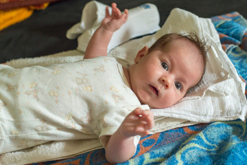 The newborn (one month old baby) lying on the bed and enjoys it