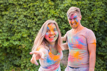 Fototapeta premium Holiday, holi and people concept - Happy couple with multicolored powder on their faces