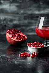Tempting pomegranate, red seeds and fresh juice with the addition of ice on a black, stone background