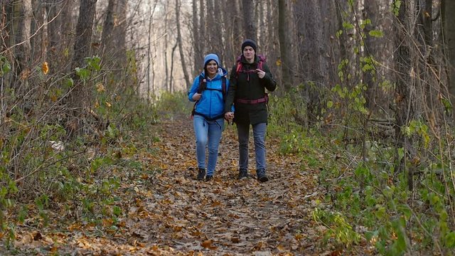 Hiking and Backpacking concept. Young Couple of travelers walking in forest in autumn day