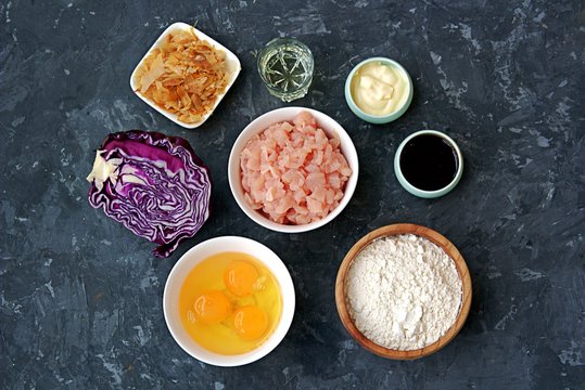 Ingredients for okonomiyaki, national Japanese dish: red cabbage, eggs, flour, mayonnaise, teriyaki sauce, sliced chicken fillet, tuna flakes, frying oil.