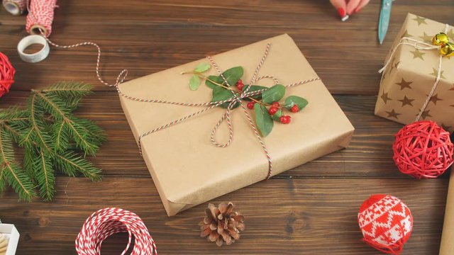 Christmas presents wrapped in eco paper with homemade decoration on wooden background with decor elements and units