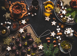 Christmas sweet background with chocolate, marshmallow, cookies, homemade pralines , cacao , nuts and spirits on dark rustic tables with vintage kitchen utensils and ingredients, top view