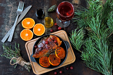 Christmas dinner. Chicken breast baked with tangerines and cranberries. Christmas tree branches and a glass of wine. Christmas mood.