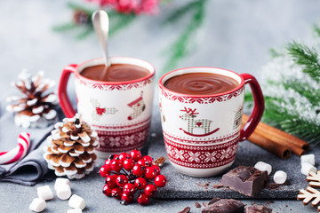 Hot chocolate with marshmallows in Christmas mugs on grey background. Copy space. Close up.