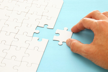 male hand putting the last piece in the puzzle.
