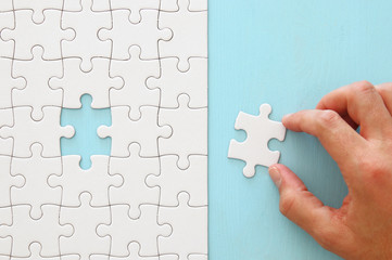 male hand putting the last piece in the puzzle.