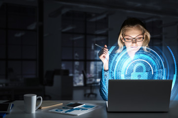 Beautiful blonde in dark office working on laptop and getting net access