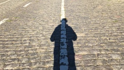 Man shadow is walking at the center of pavement road line. Slow motion 