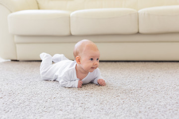 Childhood, babyhood and people concept - little baby boy or girl crawling on floor at home