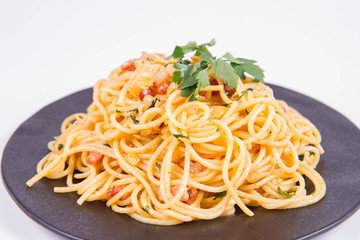 Spaghetti Carbonara with some parsley on a black plate on a white background