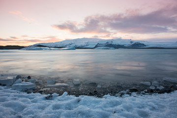 Fototapeta premium White snowy mountain on Svalbard, Norway. Ice in ocean, twilight in North pole. Pink clouds with ice floe. Beautiful landscape cold nature.