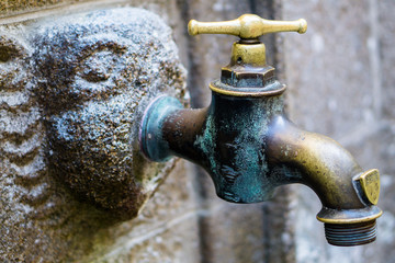 Vieux robinet en cuivre implant&eacute; sur une t&ecirc;te de gargouille