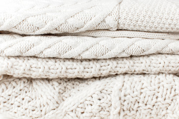Fototapeta na wymiar Texture of Two white knitted woolen sweaters pullover in a stack. Knitted background. Knitted texture. A sample of knitting from wool. Fashion Clothes Trendy Cozy Jumper. Autumn and winter clothes