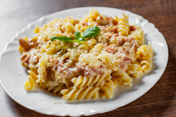 Fusilli Pasta with Carbonara Sauce and cheese in white plate on wooden table background