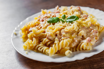Fusilli Pasta with Carbonara Sauce and cheese in white plate on wooden table background