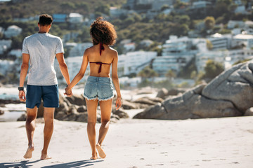 Tourist couple walking on beach on a sunny day