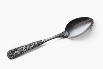 Silver ornamental vintage spoon with floral pattern on white background