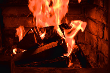 Firewood burning in fire burns in the fireplace. The brick oven gives heat and heat from the burnt logs. Burning coals and flames warm the apartment building.
