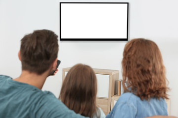 Family watching TV in room at home