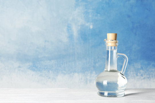 Glass jug with vinegar and space for text on color background