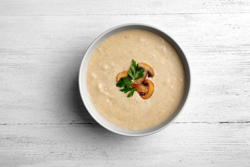 Bowl of fresh homemade mushroom soup on wooden background, top view