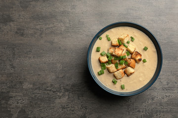 Bowl of fresh homemade mushroom soup on gray background, top view with space for text