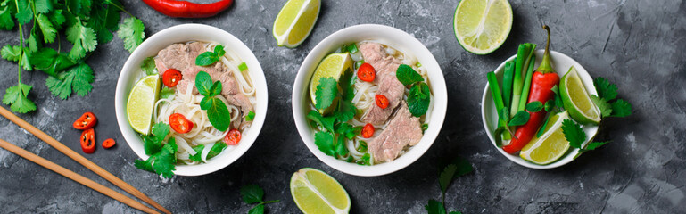 Traditional Vietnamese Soup Pho Bo with Rice Noodles, Beef and Herbs on Dark Background - obrazy, fototapety, plakaty