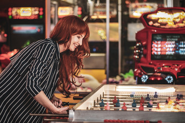beautiful redhead girl playing table hockey with passion