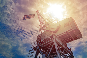 loading crane with the flag of Greece against the sky and clouds