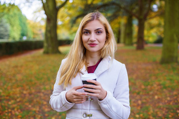 young woman with cup of coffee in city park