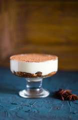 traditional Italian dessert tiramisu with chocolate sauce in glass on a dark rustic slate