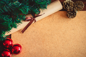 Christmas tree branch, three red balls, cones and scroll paper with a bow on the table copy space...