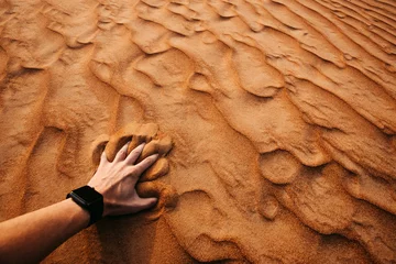 Foto auf Acrylglas Sandige Wüste Man hand is touching sand in a desert at sunset