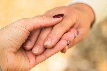 Senior and young hands, bokeh background
