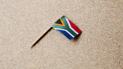 A small South African flag isolated on a wooden background. This image can be used to represent Heritage day. 